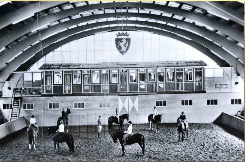 Boekelo Manege Teesink Bos jaren 70 Zeven meisjes te paard rijden hun rondjes in een overdekte zandbak van de manege te Boekelo, met instructeur.jpg