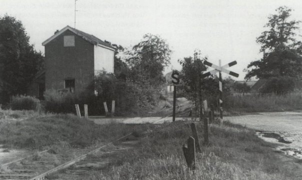Genomen naar het zuiden. Weg naar links is Voortmansweg. De Voortsweg gaat links van de foto, achter het huisje, naar rechts verder. De fotograaf staat met de rug naar het vervolg van de Voortsweg naar het noorden. Rechtsachter meen ik een schoorsteen (TTM?) te ontwaren, en een boerderijtje, maar die staat te dichtbij om Het Vrijdag te kunnen zijn. Naar midden achter splitst het spoor zich, links is het zijspoor. Dit is op de kaart van Enschede uit de jaren 30 nog goed te herkennen. Naar verluid is deze foto uit 1972, Deppenbroek is dan al gebouwd (rechtsvoor de foto). De spoorlijn zou in 1938 al gesloten zijn, dus hier al ruim 30 jaar ongebruikt.