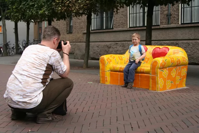 Langestraat Een vader zet zijn zoon op de foto bij het beroemdste liefdesbankje van de stad.jpg