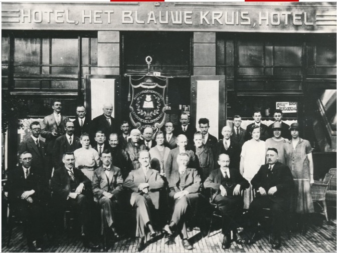 Markt 12 leden van de afdeling Enschede Lonneker voor Hotel het Blauwe Kruis met een vaandel van de Nationale Christelijke Geheelonthouders Vereniging. jaren 30.jpg