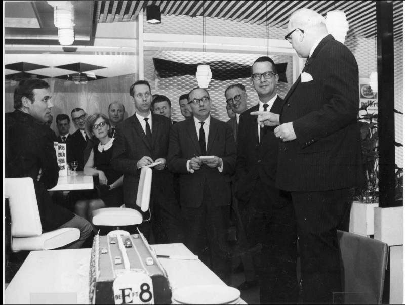 van Loenshof 15  interieur van AC restaurant met daarop een groep personen en dhr. G. J. Heijn i.v.m. de opening. Een taart met daarop de weg aanduiding E 8. 11-5-1966.jpg