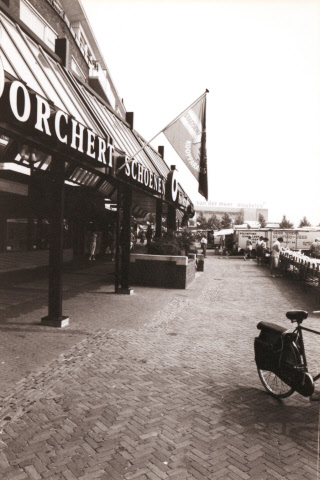 H.J. van Heekplein 18 tijdens een marktdag. Links Borchert Schoenen, op achtergrond Van der Meer Meubelen, rechts de warenmarkt 1980.jpeg