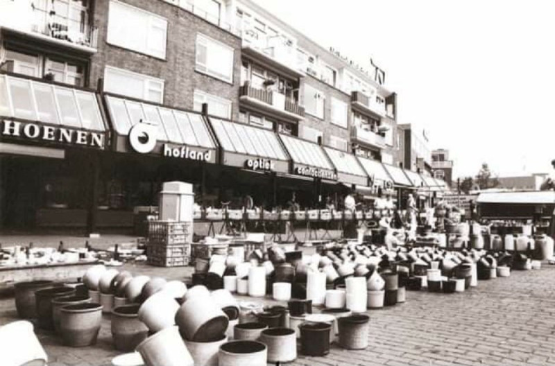 H.J. van Heekplein 18-26 Marktdag met op de achtergrond winkels van Borchert Schoenen, Hofland Optiek en Jagers Brood en Banket.jpg