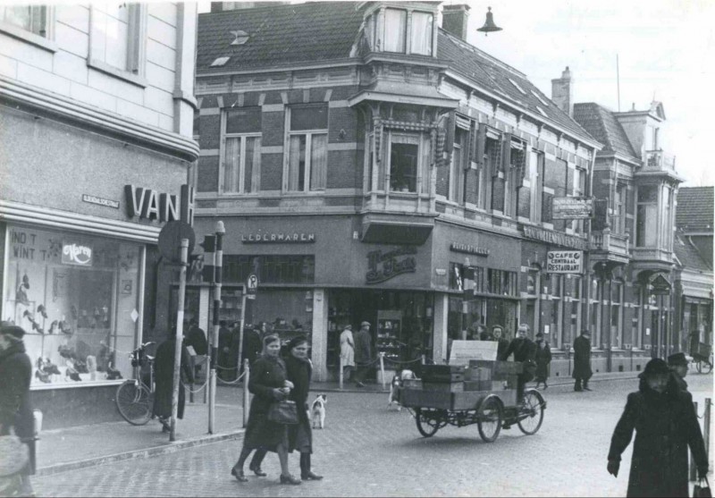 Oldenzaalsestraat 1944 Kruispunt De Klomp met de eerste stoplichten van Enschede gezien vanaf de Oldenzaalsestraat richting Kalanderstraat met Van Haren schoenen en Magasin de Paris. Man op bakfiets.jpg